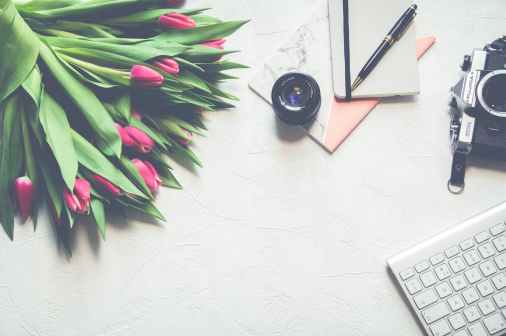 pink tulip flower bouquet near black telephoto lens and silver computer keyboard